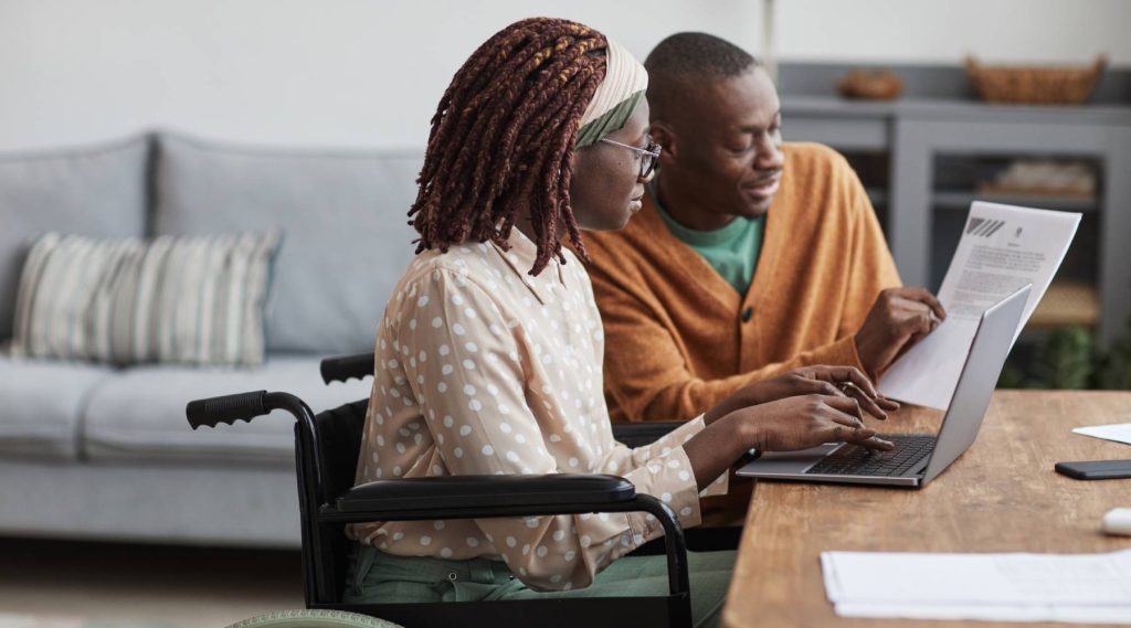 Woman-in-wheelchair-working-from-home-with-husband-1024x569
